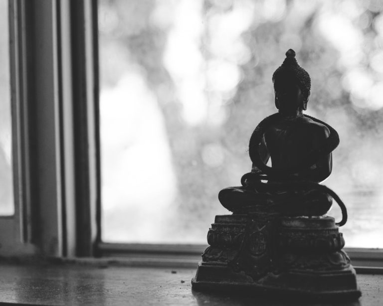 buddha statuette placed on windowsill in daylight